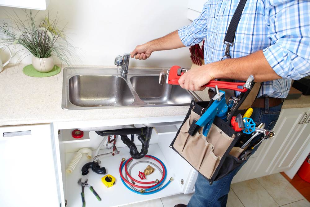 Image of a plumber working in a kitchen, featuring Hero Service Pros and highlighting the benefits of partnering with their expert plumbing services.