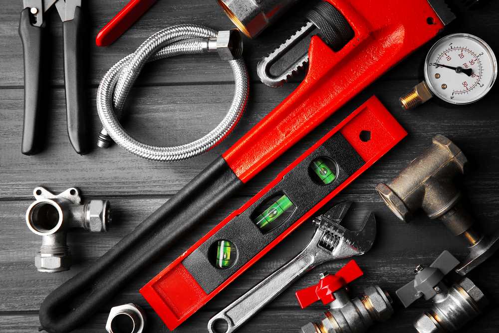 Image of plumber tools laid out on a background surface, featuring Hero Service Pros and highlighting the essential tools used by professional plumbers.