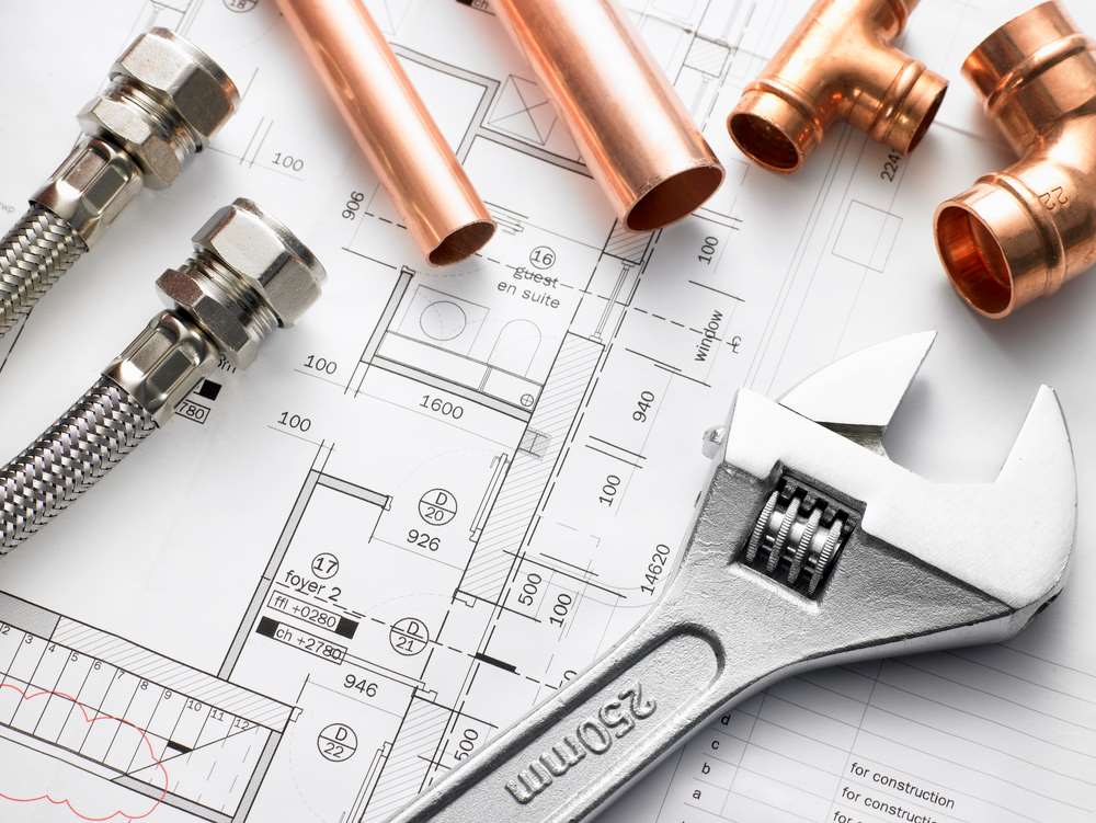 Image of plumbing equipment placed on house plans, featuring Hero Service Pros and highlighting how they help plumbers win more of the right jobs through expert support and strategy.